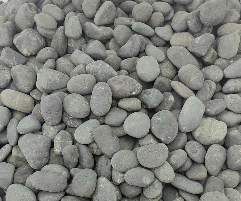 Close-up of high-quality washed black beach pebbles showing uniform size and deep gloss