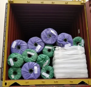 Artificial grass rolls and decorative garden pebbles packed in one container for landscaping supply